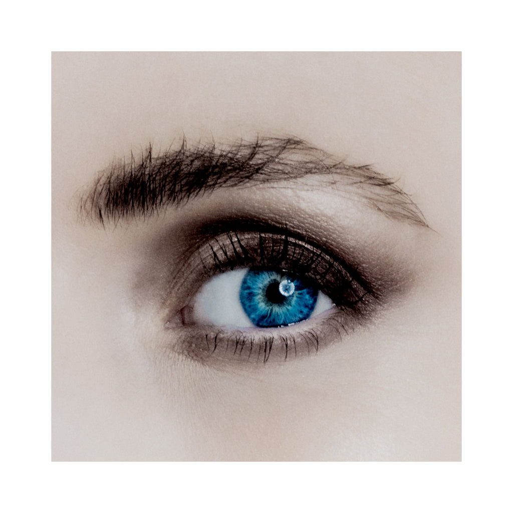 Close-up of a person's eye with blue irises on a beige background