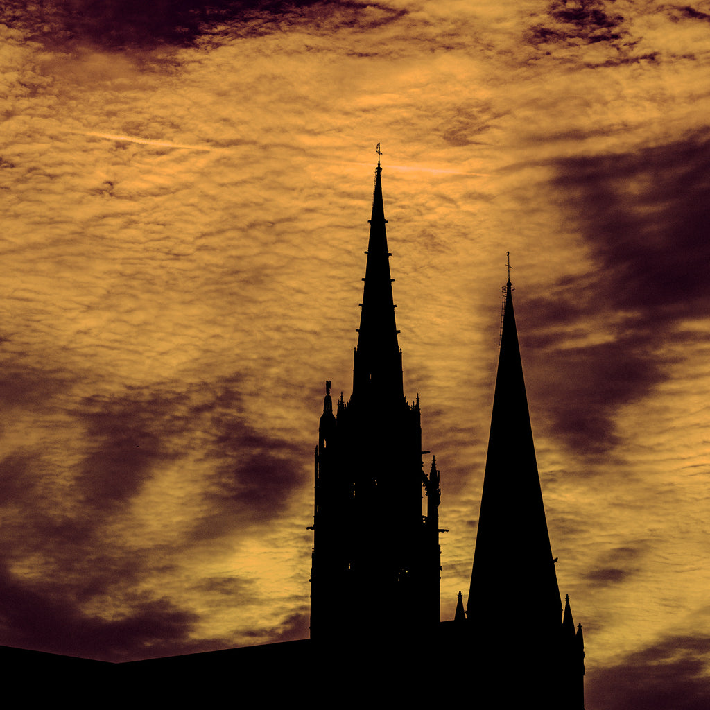 Silhouette of a cathedral against a dramatic sunset sky with orange and purple hues.