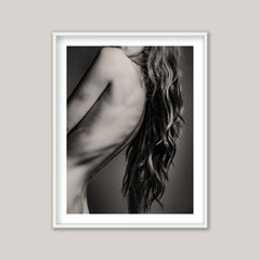 Framed black and white art print of a woman's back and hair on a plain wall.