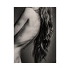 Black and white nude photo of a young woman with long hair and a blurred background